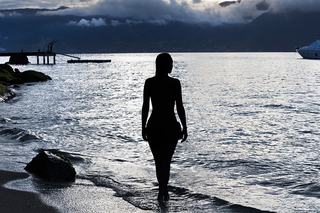 woman wearing linen wide leg trousers and silk camisole walking barefoot on beach at sunset, peaceful coastal scene, effortless summer elegance